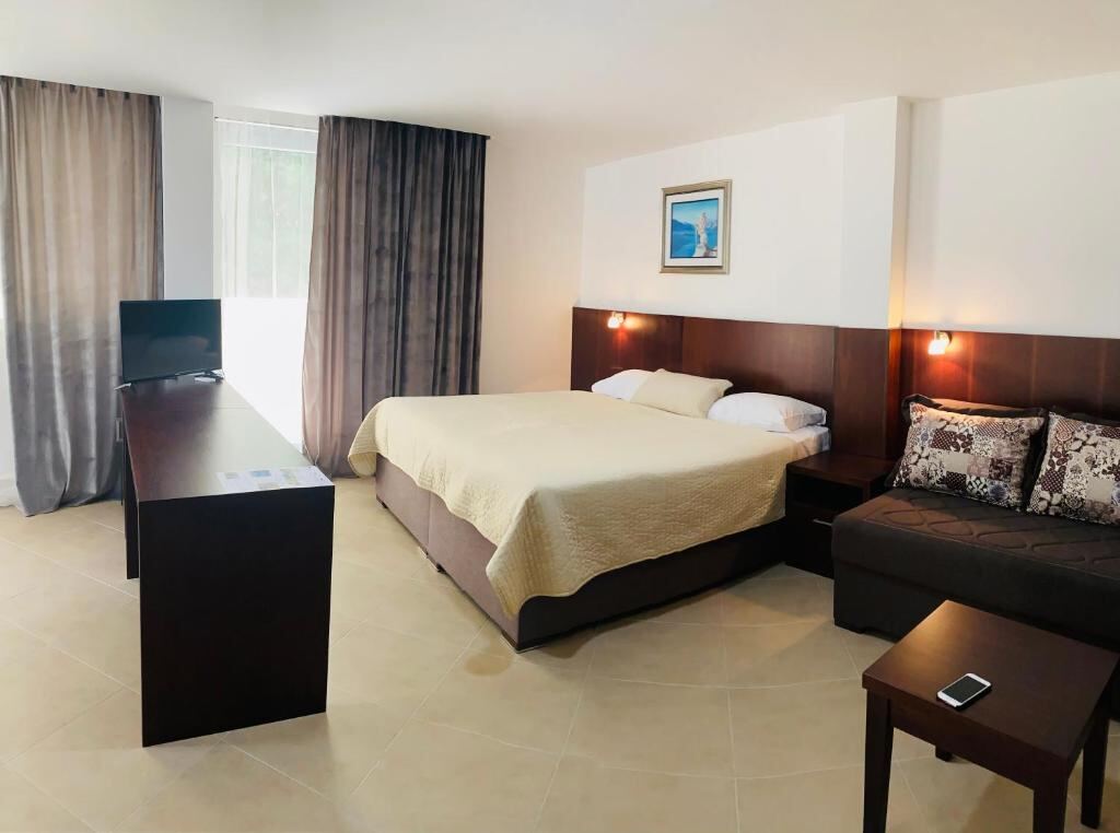 Bright room with a sofa, desk and flat-screen TV at Hotel Vienna